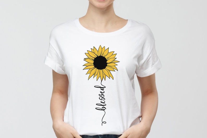 May include: White t-shirt with a yellow sunflower graphic and the word "blessed" written vertically below it.