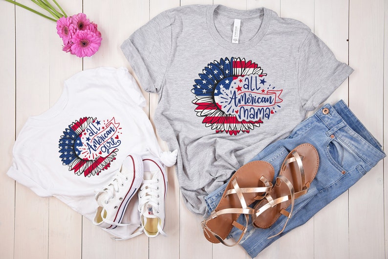 Puede incluir: Dos camisetas con un dise&ntilde;o de girasol con una bandera estadounidense y el texto "All American Girl" y "All American Mama".