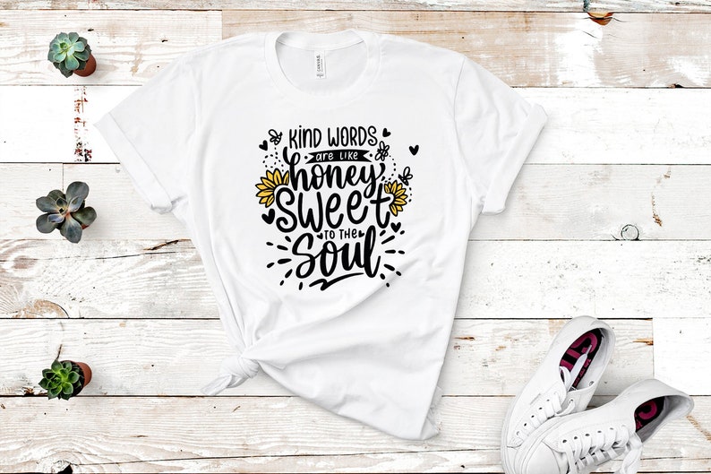May include: White t-shirt with a black and yellow graphic design that says "Kind words are like honey sweet to the soul".