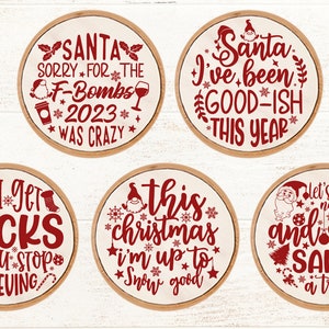 May include: Five round wooden signs with red text and images. The signs say "Santa Sorry for the F-Bombs 2023 Was Crazy", "Santa I've Been Good-ish This Year", "You Get Socks If You Stop Believing", "This Christmas I'm Up To Snow Good", and "Let's Be Naughty and Save Santa a Trip".