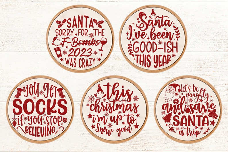 May include: Five round wooden signs with red text and images. The signs say "Santa Sorry for the F-Bombs 2023 Was Crazy", "Santa I've Been Good-ish This Year", "You Get Socks If You Stop Believing", "This Christmas I'm Up To Snow Good", and "Let's Be Naughty and Save Santa a Trip".