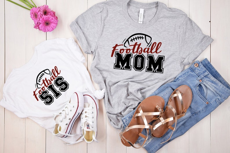May include: A grey t-shirt with the text Football MOM and a football graphic, a white t-shirt with the text Football SIS and a football graphic, blue denim jeans, a pair of white canvas sneakers, and a pair of metallic gold strappy sandals.
