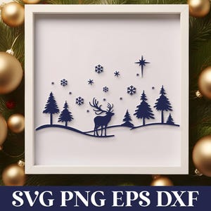 May include: A white frame with a blue silhouette of a deer standing in a snowy forest with a star above. The image is surrounded by gold ornaments and green pine branches.