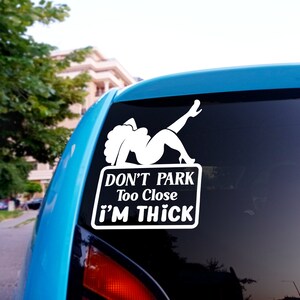Puede incluir: Pegatina de vinilo blanco con una silueta de mujer con el texto "Don't Park Too Close I'm Thick" en un coche azul.