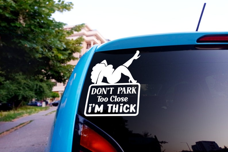 Puede incluir: Pegatina de vinilo blanco con una silueta de mujer con el texto "Don't Park Too Close I'm Thick" en un coche azul.