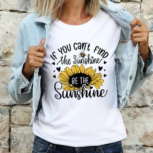 May include: White t-shirt with a sunflower graphic and the text "If you can't find the sunshine, be the sunshine".