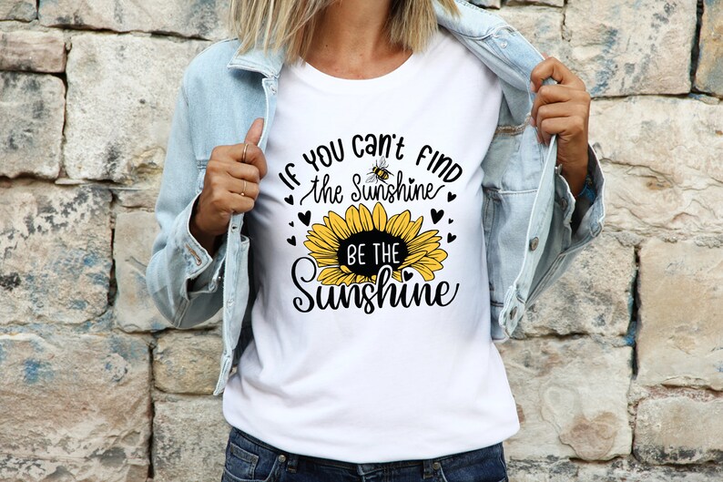 May include: White t-shirt with a sunflower graphic and the text "If you can't find the sunshine, be the sunshine".