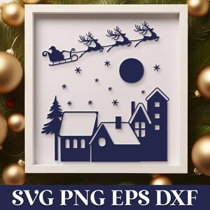 May include: A framed Christmas-themed shadow box featuring a silhouette of Santa Claus in a sleigh pulled by reindeer, flying over a village. The design includes a moon, stars, and houses. The frame is surrounded by gold ornaments and evergreen branches.