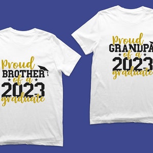 May include: Two white t-shirts with black and gold text. One shirt says "Proud Brother of a 2023 Graduate" and the other says "Proud Grandpa of a 2023 Graduate".