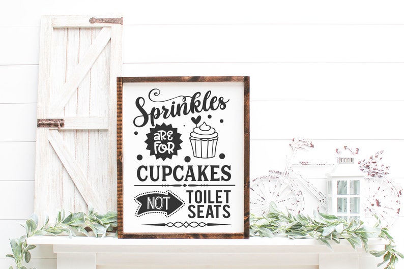 May include: A wooden sign with the text "Sprinkles are for cupcakes, not toilet seats". The sign features a black and white illustration of a cupcake with sprinkles.