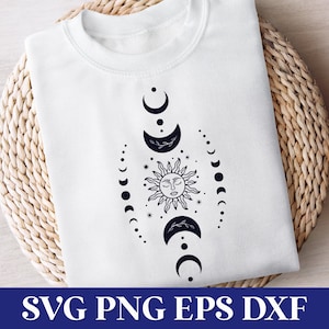 May include: A white t-shirt featuring a black and white design of a sun and moon phases. The design is centred on the shirt and includes a stylised sun with a face and a series of crescent moons.