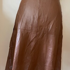 May include: A brown leather skirt with a high waist and a flared silhouette.
