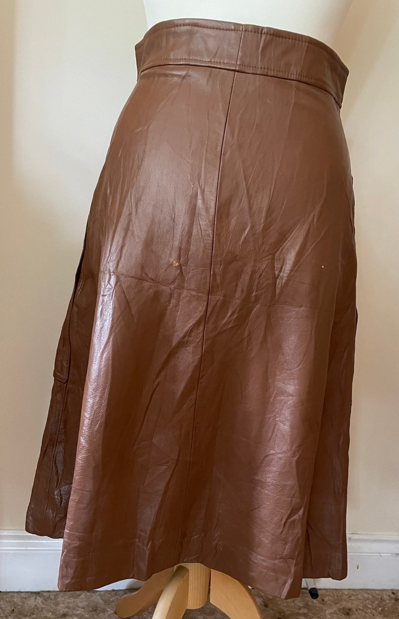 May include: A brown leather skirt with a high waist and a flared silhouette.