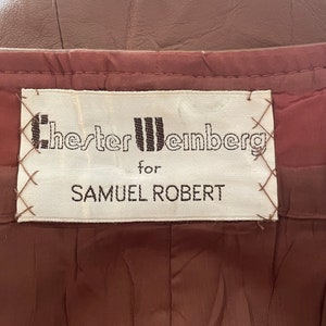 May include: A white label with black text that reads "Chester Weinberg for Samuel Robert". The label is sewn onto a brown fabric.