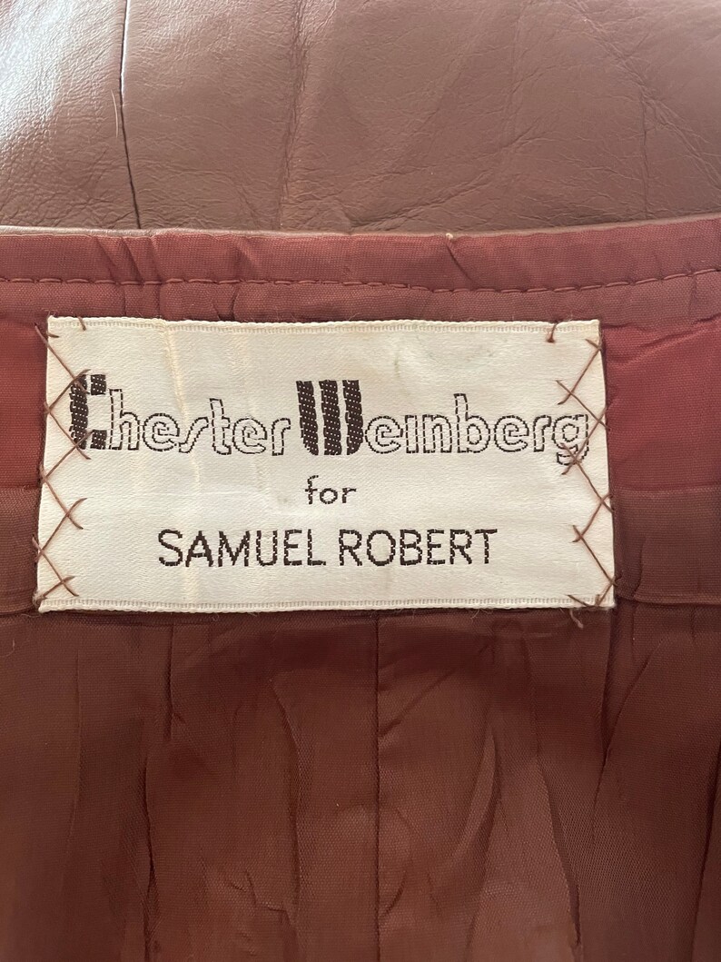 May include: A white label with black text that reads "Chester Weinberg for Samuel Robert". The label is sewn onto a brown fabric.