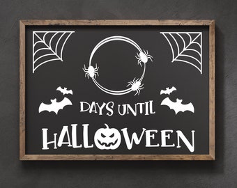 May include: A black chalkboard with a wooden frame displays a Halloween countdown. The chalkboard features white text that reads "Days Until Halloween" with a pumpkin and bats. There are also spiderwebs and spiders on the chalkboard.