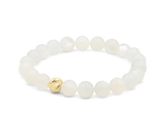 May include: White beaded bracelet with a gold accent bead. The bracelet features round, opaque white beads strung together with a single textured gold bead. The jewelry is displayed on a white background.