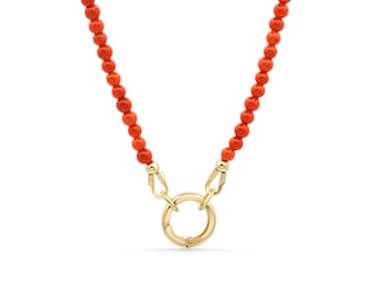 May include: A necklace featuring a strand of vibrant orange beads that connect to a central gold-toned circular spring ring clasp. The beads are uniform in size and shape, creating a continuous line that leads to the polished metal hardware.