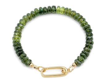 May include: A bracelet featuring a continuous strand of faceted, olive-green gemstone beads. The ends of the bead strand are connected by a polished gold-tone metal oval link clasp, which serves as the primary closure mechanism for the jewelry piece.
