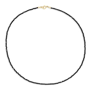 May include: A delicate necklace composed of small, faceted black beads strung in a continuous circular pattern. The piece is secured with a polished gold-toned metal spring ring clasp at the top, providing a secure closure for the beaded strand.