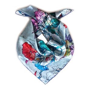 May include: A light blue silk scarf with a floral print of colourful flowers and leaves. The scarf is folded in a triangular shape.