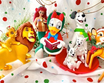 May include: A set of nine Christmas ornaments featuring various Disney characters, including Winnie the Pooh, Simba,  Ariel,  Daisy Duck,  and  a Dalmatian. The ornaments are made of plastic and feature a variety of colors, including red, green, yellow, and blue.