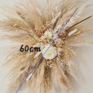 May include: A large, cream-colored dried flower arrangement with pampas grass and white flowers. The arrangement measures 60 cm in diameter.