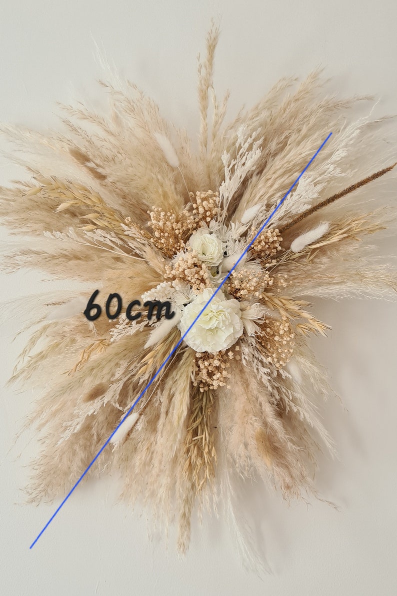 May include: A large, cream-colored dried flower arrangement with pampas grass and white flowers. The arrangement measures 60 cm in diameter.