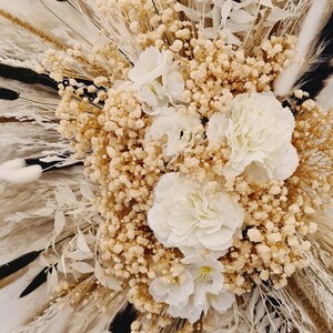May include: A dried flower arrangement with white and beige pampas grass, white bunny tails, and white and beige dried flowers.