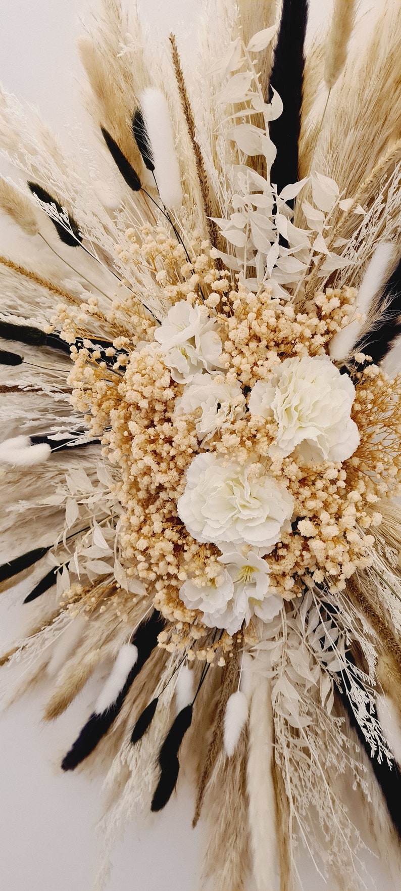 May include: A dried flower arrangement with white and beige pampas grass, white bunny tails, and white and beige dried flowers.