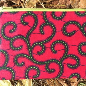 May include: A red zippered pouch with a green and black swirling pattern.
