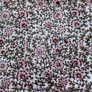 May include: White fabric with a repeating pattern of burgundy and green floral designs. The pattern features stylized flowers and leaves.