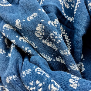 May include: A close-up of a blue fabric with a white paisley pattern. The fabric is folded and textured.