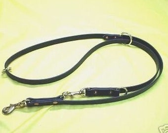 May include: A black leather dog lead with two metal clips and a metal ring. The lead is designed for walking two dogs.