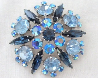 May include: A vintage brooch with a cluster of blue and dark blue rhinestones in a floral design.