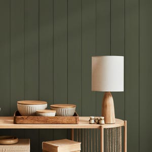 May include: A wooden console table with a lamp, decorative bowls, and a tray. The lamp has a beige shade and a wooden base. The bowls are white with wooden lids. The background is a dark green vertical panel wall.