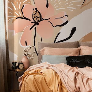 May include: A bedroom scene featuring a bed with peach and gold bedding, a black pillow, and a floral wall mural. A small side table holds a vase, clock, and decorative items. The room has a soft, inviting aesthetic.