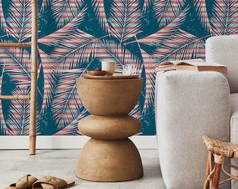 Può includere: Un tavolino da salotto in legno con un design unico a tre livelli. Il tavolino è posizionato contro un muro blu-verde con un motivo a foglie di palma rosa e bianco.