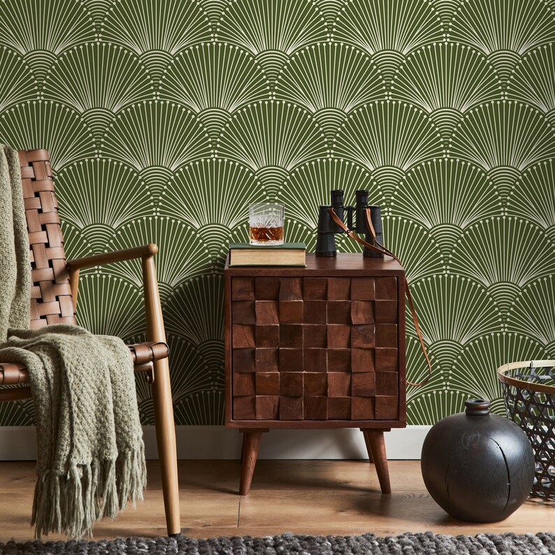 K&ouml;nnte beinhalten: Eine dunkelgr&uuml;ne Tapete mit einem wei&szlig;en geometrischen Muster aus &uuml;berlappenden F&auml;cher. Ein Holz-Beistelltisch mit quadratischer Platte und vier Beinen steht vor der Tapete. Ein Glas Fl&uuml;ssigkeit steht auf einem Buch auf dem Tisch. Ein Fernglas und eine schwarze Vase stehen ebenfalls auf dem Tisch.