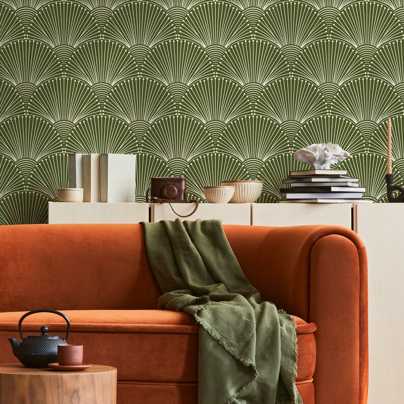 K&ouml;nnte beinhalten: Eine gr&uuml;n-wei&szlig;e geometrische Tapete mit einem braunen Samtsofa und einer gr&uuml;nen Wolldecke. Das Sofa steht vor einem wei&szlig;en Regal mit B&uuml;chern und Dekoartikeln.