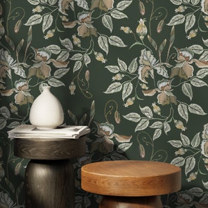 May include: A dark green wallpaper with a floral pattern. The pattern features white embroidered flowers and leaves. The wallpaper is displayed on a wall with two wooden stools in front of it.