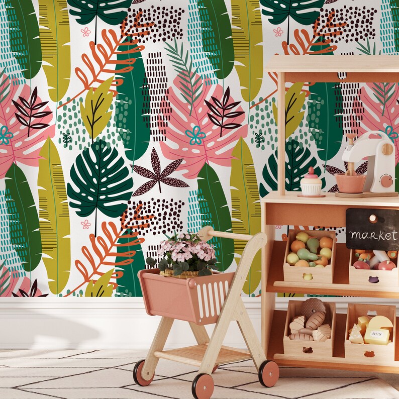 May include: A play kitchen with a chalkboard sign that says "market" and shelves stocked with toy fruits and vegetables. A pink toy shopping cart is in the foreground with a potted plant inside.