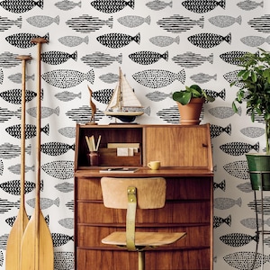 May include: A room scene featuring a wooden desk, chair, and decorative items against a white wall with a black fish pattern. The scene includes a small sailboat, potted plants, and wooden oars.