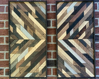 May include: Two rectangular wooden wall art pieces with a geometric pattern of various shades of brown, black, and white wood. The pieces are framed in black and are hung on a brick wall.
