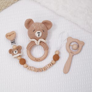 以下が含まれることがあります： 編みぐるみのかわいいクマのガラガラ、ビーズ付きの木製歯固め、そして「Jessica」という名前が刻まれた木製ビーズのネックレスがセットになった、赤ちゃん用の木製歯固めセットです。