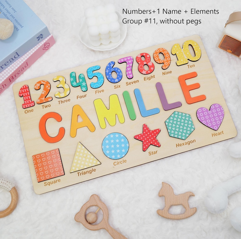 Op de afbeelding: Een houten puzzelbord met de naam CAMILLE in gekleurde letters, de cijfers &eacute;&eacute;n tot en met tien, en diverse vormen zoals een vierkant, driehoek, cirkel, ster, zeshoek en hart, elk gelabeld met de bijbehorende naam in het Engels.