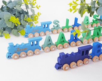 May include: A blue and green wooden train set with the names "Aaron" and "Silas" spelled out on the train cars. The train cars are decorated with colorful letters and have wooden wheels.