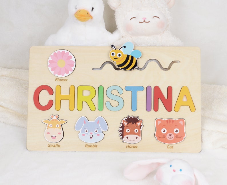 May include: A wooden personalised puzzle featuring the name Christina. The puzzle includes a bee, flower, giraffe, rabbit, horse and cat. This puzzle is a great educational toy for children.