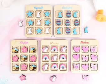 Può includere: Nove tavoli da gioco in legno con diversi temi e nomi. I tavoli hanno nove caselle ciascuno e sono progettati per giochi di abbinamento. I temi includono coniglietti, uova di Pasqua, api, fiori, arcobaleni, unicorni, cuori e farfalle.