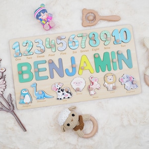 May include: A wooden puzzle featuring the name "BENJAMIN" and numbers 1-10. The puzzle includes animal shapes. The numbers and letters are in various colors. Additional toys are visible in the image.